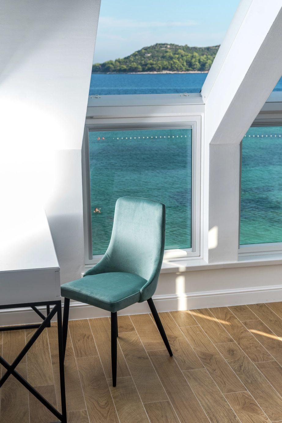 finestre per tetti affiancate da cui si vede un mare azzurro chiaro.
