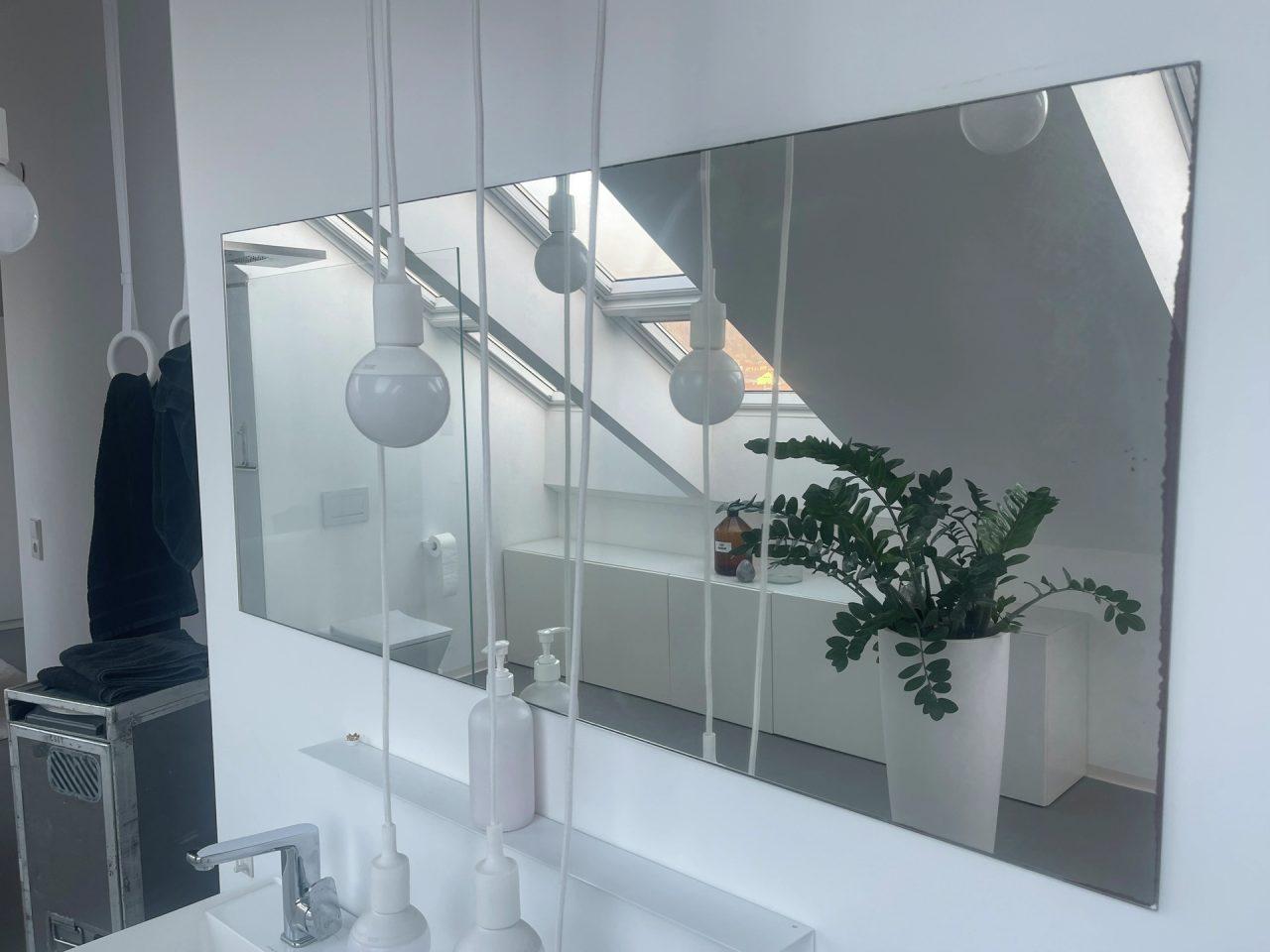 bagno in mansarda con specchio nel quale si vedono luminose finestre per tetti