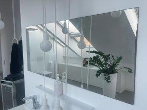 bagno in mansarda con specchio nel quale si vedono luminose finestre per tetti